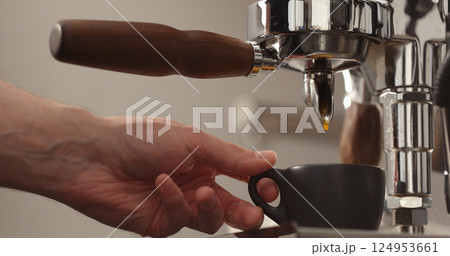 espresso pour from single spout portafilter into black cup 124953661