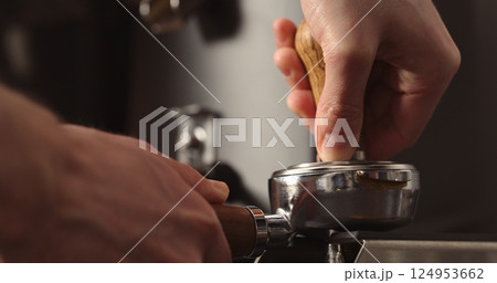 man tamping freshly ground coffee in portafilter man tamping freshly ground coffee in portafilter 124953662