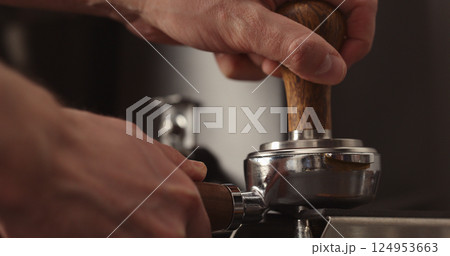 man tamping freshly ground coffee in portafilter man tamping freshly ground coffee in portafilter 124953663