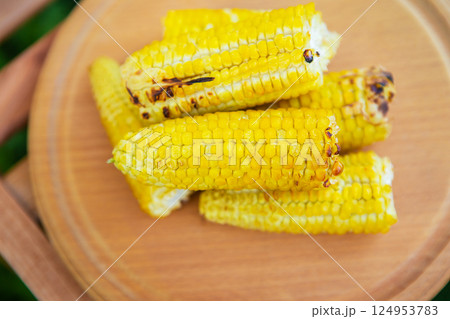 Delicious, sweet young grilled popcorn lies on a wooden board, outdoor recreation, proper nutrition. Close-up. Delicious, sweet young grilled popcorn lies on a wooden board, outdoor recreation, proper nutrition. Close-up. 124953783