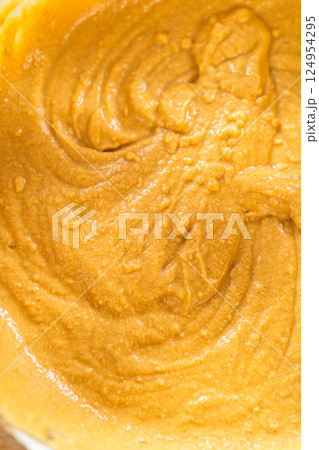 In a glass mixing bowl, a large hand whisk expertly blends the ingredients for a delectable gingerbread bundt cake with caramel frosting. 124954295