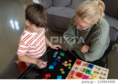 Child learning to count with wooden numbers and adult guidance at home 124954409