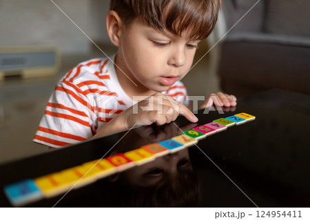 Child counts while playing with wooden tiles 124954411