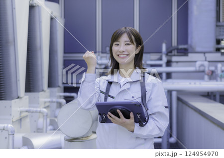 タブレットを持ってガッツポーズする笑顔の若い女性作業員　撮影協力：学校法人電波学園 東京電子専門学校 124954970