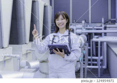 タブレットを持って指さしをする笑顔の若い女性作業員　撮影協力：学校法人電波学園 東京電子専門学校 124954971