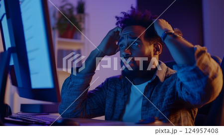Shocked African American man reacting to computer error at night 124957408