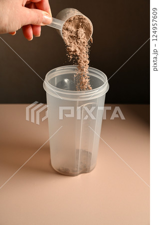 Pouring chocolate protein powder in a shaker, food supplement concept Pouring chocolate protein powder in a shaker, food supplement concept 124957609