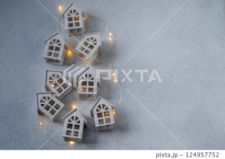 New Year's garland. Christmas background. Gray wooden toy houses. Copy space New Year's garland. Christmas background. Gray wooden toy houses. Copy space 124957752