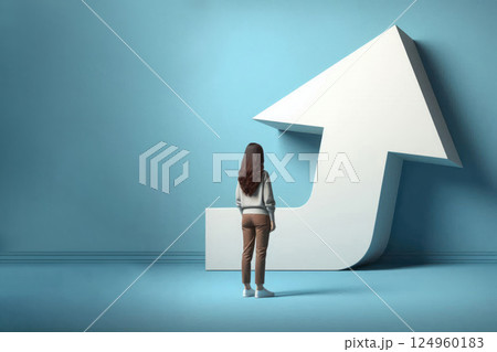 A woman looks at a large white arrow, symbolizing the goal and the path. Space for text. 124960183