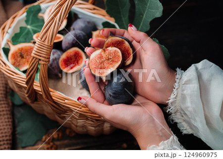 Woman hands fresh ripe fig, demonstrates juicy pulp inside fruit. Ficus carica. 124960975