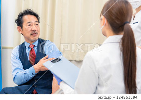 病院で男性患者の問診をする女性医師 病院で男性患者の問診をする女性医師 124961394