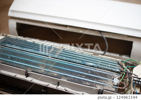Dirty and disassembled wall-mounted air conditioner unit, showing internal components and dust. repair or cleaning. 124961594