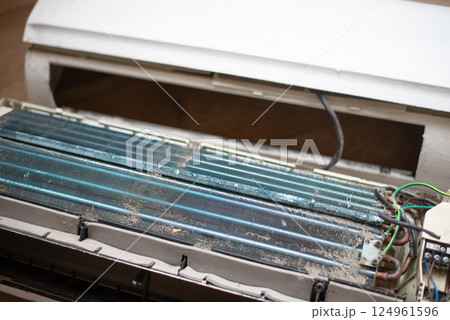 Dirty and disassembled wall-mounted air conditioner unit, showing internal components and dust. repair or cleaning. Dirty and disassembled wall-mounted air conditioner unit, showing internal components and dust. repair or cleaning. 124961596