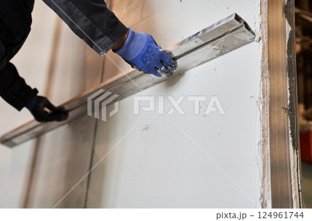 Close-up of the wall alignment rule tool. A man is smoothing a layer of plaster on a wall. With space to copy. High quality photo 124961744