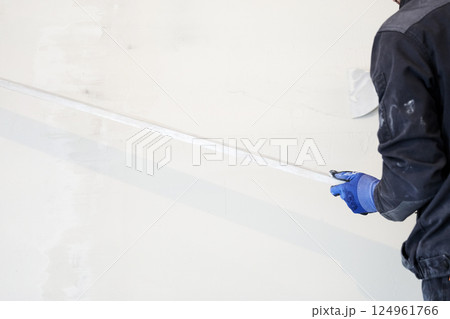 A metal rule for leveling plaster on walls. Applying gypsum plaster in a mechanized way to the wall. High quality photo 124961766