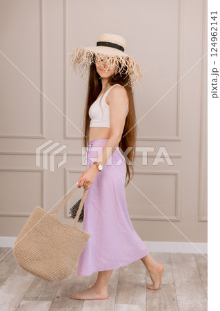 Woman in summer outfit with straw hat and jute bag, perfect for vacation, beach or boho fashion shoots. Woman in summer outfit with straw hat and jute bag, perfect for vacation, beach or boho fashion shoots. 124962141
