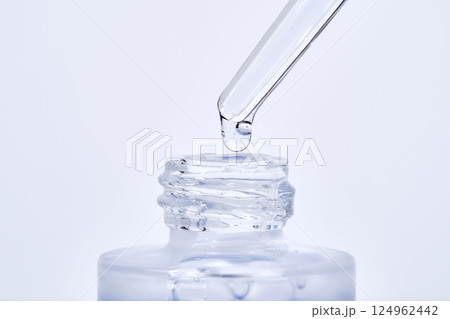 The blue serum drips from the dropper into the bottle. The blue serum drips from the dropper into the bottle. 124962442