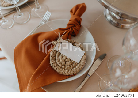 On a table, there is a plate with a napkin that has a tag attached to it On a table, there is a plate with a napkin that has a tag attached to it 124963771