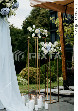 A wedding arch with vibrant flowers and candles on a lovely patio 124963794