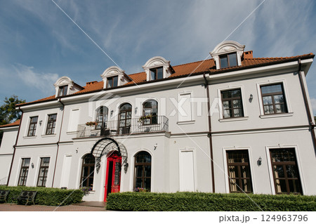 A large white building features a striking red door and roof 124963796