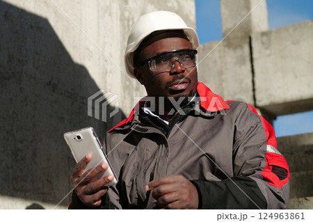 African american workman with smartphone at construction site 124963861