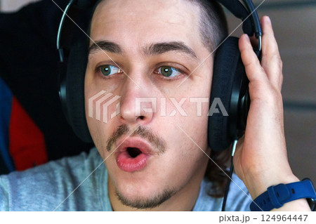 Enthusiastic conversation fills the air as a man wearing headphones interacts with friends during an intense gaming 124964447