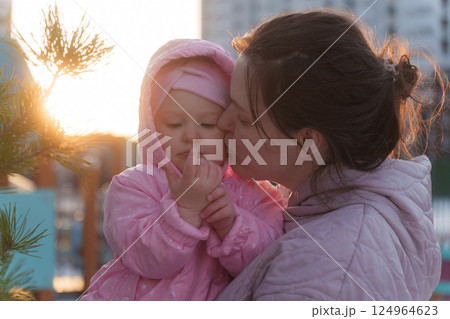 Mother kisses daughter in cozy outdoor setting during sunset, capturing a tender moment between parent and child in winter Mother kisses daughter in cozy outdoor setting during sunset, capturing a tender moment between parent and child in winter 124964623