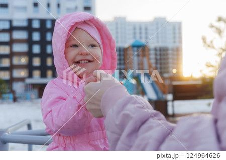 Happy child in pink jacket enjoys playtime at playground during sunset in a modern urban setting 124964626
