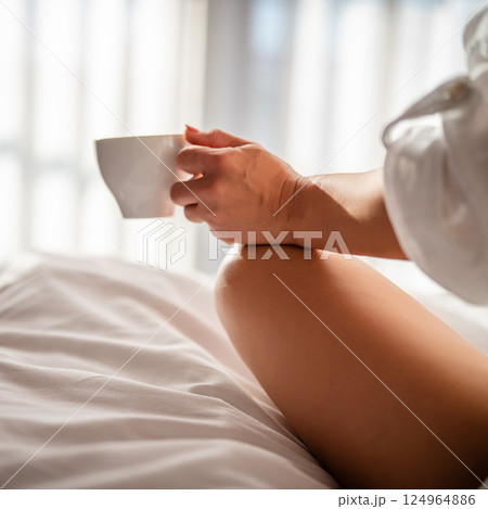 Woman with cup of coffee in the morning under the blanket at home Woman with cup of coffee in the morning under the blanket at home 124964886