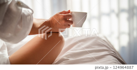Woman with cup of coffee in the morning under the blanket at home Woman with cup of coffee in the morning under the blanket at home 124964887