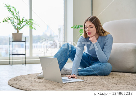 Young woman using laptop, sitting on floor at home 124965238