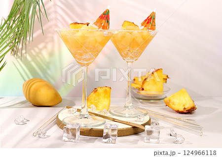 Pineapple alcoholic cocktail Margarita in glasses with lime and pineapple slices rim and umbrella. Cold frozen punch with ice pieces. Summer tropical party concept, diet drink for weight loss. 124966118