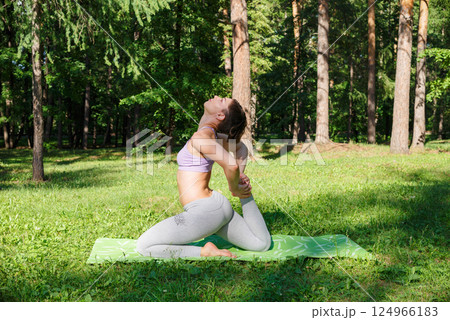 Beautiful girl practices yoga in the park. 124966183