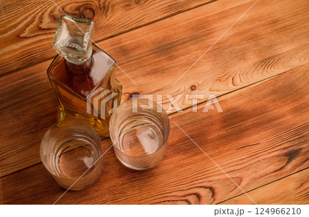 Two glasses and a decanter with whiskey on a wooden table Two glasses and a decanter with whiskey on a wooden table 124966210