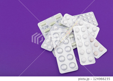 Glass thermometer between red pills and purple capsules Glass thermometer between red pills and purple capsules 124966235