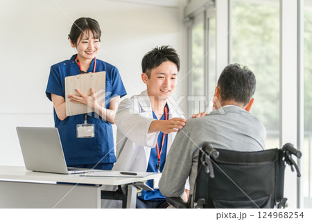 肩こり・肩を痛がる高齢者・シニア男性と介護施設・病院で働く整形外科の医師・看護師 124968254