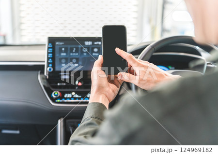 自動車の車内でスマホを使う自動車整備士の男性 自動車の車内でスマホを使う自動車整備士の男性 124969182