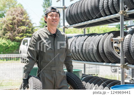 タイヤラックからスタットレスタイヤを運ぶ整備士・メカニックの男性 タイヤラックからスタットレスタイヤを運ぶ整備士・メカニックの男性 124969441
