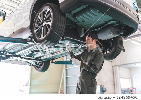 自動車の下回りをライトで照らしながらチェックする自動車整備士の男性 自動車の下回りをライトで照らしながらチェックする自動車整備士の男性 124969460