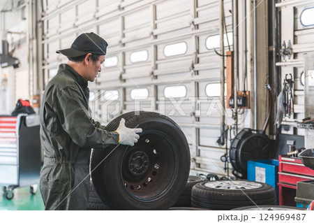 自動車整備工場でタイヤを運ぶ男性メカニック(肉体労働・重労働・重い・腰痛) 自動車整備工場でタイヤを運ぶ男性メカニック(肉体労働・重労働・重い・腰痛) 124969487