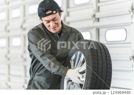 自動車整備工場でタイヤを運ぶ男性メカニック(肉体労働・重労働・重い・腰痛) 自動車整備工場でタイヤを運ぶ男性メカニック(肉体労働・重労働・重い・腰痛) 124969490
