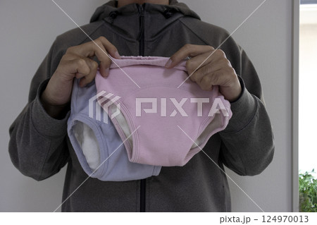 暗い部屋で子供のパンツを持つ男性。犯罪イメージ 124970013