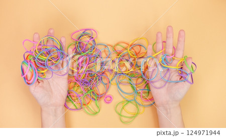 A vibrant assortment of colorful rubber bands beautifully tangled together on a peach background 124971944