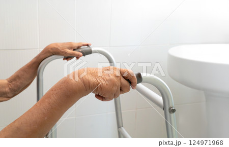 Elderly woman using walker in restroom for safety. 124971968