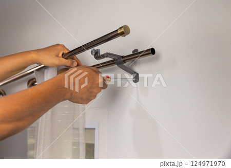 Worker repairman hanging and fixing the curtain on the window. 124971970