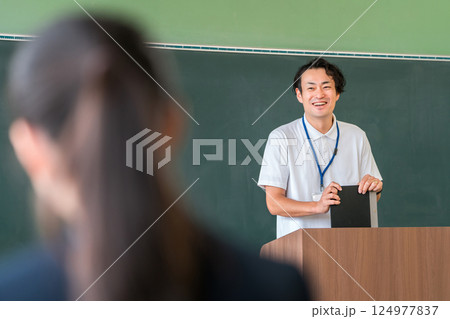 教室の黒板の前で授業をする男性教師 124977837