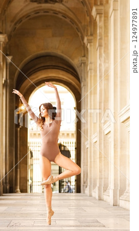 Ballet dancer performing pose in urban archway 124977891