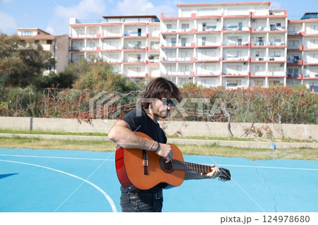 Long Hair Man Plays Classical Guitar Unleashed Outside In Blue Field 124978680