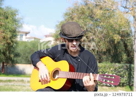Playing the Guitar Outdoor to Train the Mind for Concentration and Exercise Playing the Guitar Outdoor to Train the Mind for Concentration and Exercise 124978711