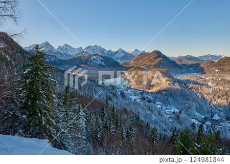 Beautiful winter morning landscape with snowy mountains and a serene lake, icy landscape surrounding majestic peaks, dawn light in January 124981844
